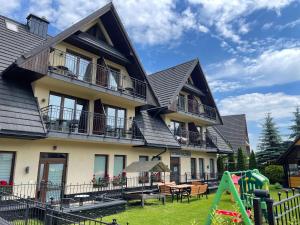 una casa con un parque infantil delante de ella en Apartamenty Viva Tatry, en Zakopane