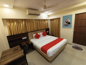 1 dormitorio con 1 cama grande con almohadas rojas en Payal Hotel Panvel en Navi Mumbai
