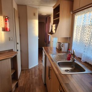 a small kitchen with a sink and a window at 3 BEDROOM CARAVAN AT THE GRANGE HOLIDAY PARK, CHAPEL ROAD INGOLDMELLS in Addlethorpe