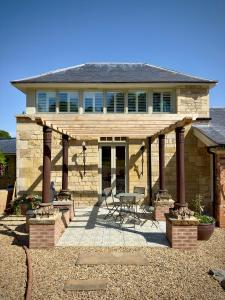 a stone house with a wooden pergola at Normanton Park House - Luxury Rutland Water Home in Oakham