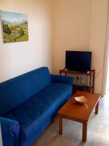 Una sala de estar con un sofá azul y una mesa. en Ηλιαχτίδα Iliachtida apartment, en Chios