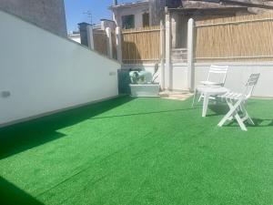 eine Terrasse mit grünem Gras und zwei Stühlen darauf in der Unterkunft CASA GIOBERTI in Castellana Grotte