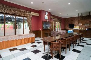 un restaurant avec une grande table et des chaises dans l'établissement Puri Saras Bintaro Syariah Mitra RedDoorz, à Jurangmanggu