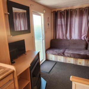 a small room with a bed and a desk with a television at 3 BEDROOM CARAVAN AT THE GRANGE HOLIDAY PARK, CHAPEL ROAD INGOLDMELLS in Addlethorpe