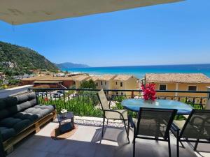 a balcony with a couch and a table and the ocean at Corfu Glyfada Menigos Resort 149 in Glyfada