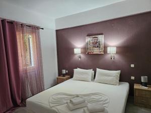 a bedroom with a white bed with a purple wall at Corfu Glyfada Menigos Resort 149 in Glyfada