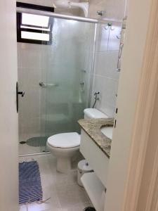 uma casa de banho com um WC e uma cabina de duche em vidro. em Condominio com muita diversão Toninhas em Ubatuba