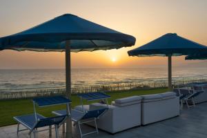 eine Terrasse mit Stühlen, Sonnenschirmen und dem Meer in der Unterkunft Pickalbatros White Beach Taghazout - Adults Friendly 16 Years Plus - Ultra All Inclusive in Taghazout