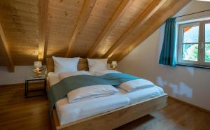 a bed in a room with a wooden ceiling at Ferienwohnungen Zober am Mühlbach in Oberammergau