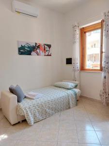a bedroom with a bed and a couch and a window at casa delle margherite Ladispoli in Ladispoli
