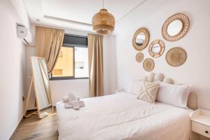una camera da letto con un letto bianco e specchi sul muro di TT Holidays Cosy apartment Rabat City Center a Rabat