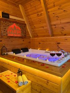 bañera de hidromasaje en una habitación de madera con 2 copas de vino en Meşe Dağ Evleri en Rize