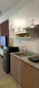 a kitchen with a sink and a refrigerator at Mesavirre Garden Residence in Bacolod