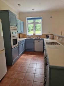 a kitchen with blue cabinets and a tile floor at Country retreat near sea and South Downs, on National Cycle Network in Polegate