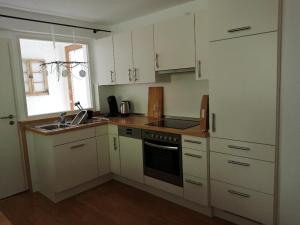 uma cozinha com armários brancos e um lavatório em Ferienwohnung deine Rauszeit em Seebach