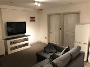 a living room with a couch and a flat screen tv at Modern 1 bedroom apartment close to Penzance town centre. in Penzance