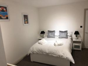 um quarto com uma cama branca com duas mesas de cabeceira em Modern 1 bedroom apartment close to Penzance town centre. em Penzance