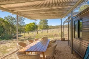 a wooden table and chairs on a patio at Widgereedoo Farm. Vineyard views. Peaceful retreat. in Tamaree