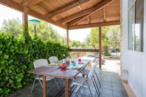 einen Holztisch und Stühle auf einer Terrasse in der Unterkunft Villa Blanca - Villa intera con trullo e piscina in Putignano