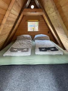 a bed in the attic of a log cabin at Abenteuercamp Schaeferhof Hütten oder Stellplatz für kleinen Camper oder Zelt in Cottbus