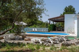 ein Schwimmbad mit einem Haufen Stühle drum herum in der Unterkunft Villa Blanca - Villa intera con trullo e piscina in Putignano