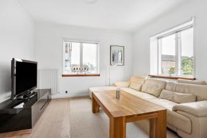een witte woonkamer met een bank en een tv bij Cozy 2-Bed Apartment in Aalborg in Aalborg