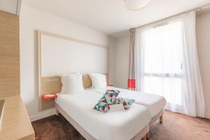 a bedroom with a large white bed with a window at Appart'City Confort Bordeaux Chartrons in Bordeaux