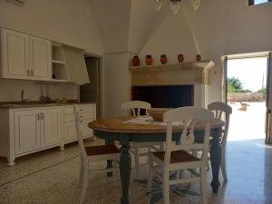 uma cozinha com uma mesa e cadeiras e uma lareira em masseria Carlini em Acaya