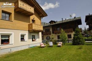 a house with a yard with chairs and a balcony at Abete Rosso Nuovissimo ed in centro a Livigno in Livigno