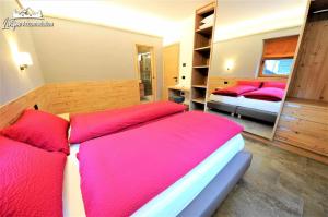 una camera con 2 letti con cuscini rossi di Abete Rosso Nuovissimo ed in centro a Livigno a Livigno