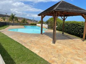 een houten prieel naast een zwembad bij LE LAGON La Saline Les Bains vue mer, piscine in La Saline les Bains