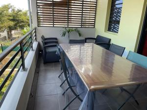 een balkon met een houten tafel en stoelen bij LE LAGON La Saline Les Bains vue mer, piscine in La Saline les Bains +2 foto's