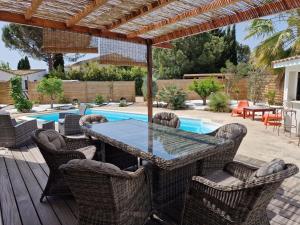 eine Terrasse mit einem Tisch, Stühlen und einem Pool in der Unterkunft villa ORANANS in Marseillan
