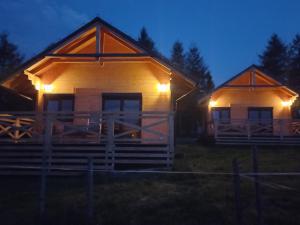 two wooden houses with lights on them at night at Bieszczadzka Polana - domki turystyczne/sezonowe in Lutowiska