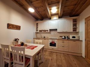 a kitchen with white cabinets and a table with chairs at Apartmán Jezerné in Velké Karlovice