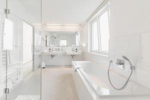 a white bathroom with a tub and a sink at Seehotel Dr. Jilly in Pörtschach am Wörthersee