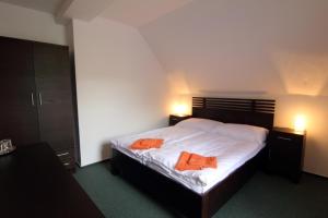 a bedroom with a bed with two orange towels on it at Pension Troll in Rokytnice nad Jizerou