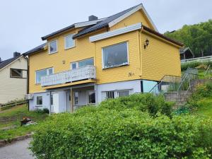 Una casa amarilla con balcón en la parte superior. en SAGA Overnatting en Kirkenes