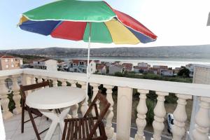 stół i krzesła na balkonie z parasolem w obiekcie Apartments Antonio w mieście Pag