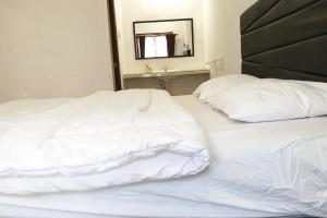 two white beds in a bedroom with a mirror at Anugrah Bromo Homestay at Desa Wisata Bromo Mitra RedDoorz in Tosari +2 photos