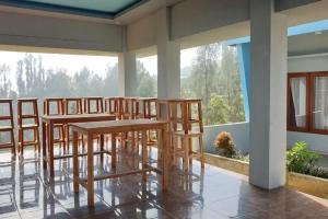 a row of wooden tables and chairs on a balcony at Anugrah Bromo Homestay at Desa Wisata Bromo Mitra RedDoorz in Tosari