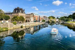 a small boat in a river in front of a building at Maison cosy avec parking gratuit in Jarnac +1 photo
