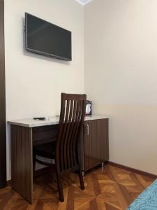 einen Schreibtisch mit Stuhl und einen TV an der Wand in der Unterkunft Guest House Ritsa in Gagra