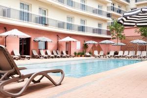 una piscina en un hotel con sillas y sombrillas en tent Lloret de Mar, en Lloret de Mar