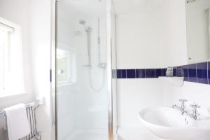biała łazienka z prysznicem i umywalką w obiekcie Bull Hotel by Greene King Inns w mieście Halstead