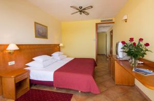 a hotel room with a bed with a red blanket at Hotel Zora in Primošten