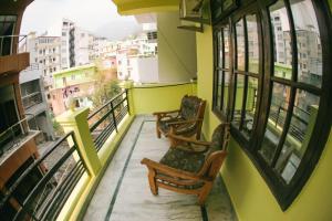 2 stoelen op een balkon met uitzicht op de stad bij Maa Vaibhav Laxmi Guest House in Rishīkesh