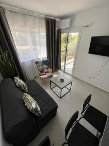 ein Wohnzimmer mit einem schwarzen Sofa und Stühlen in der Unterkunft Early Bird in Paralimni