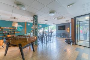 Una habitación con una mesa de ping pong y sillas. en Appart'City Confort Bordeaux Chartrons, en Burdeos