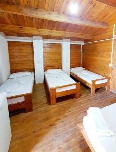 two beds in a room with wooden walls at TONEDA Seaside Bungalows in Dhërmi +14 photos